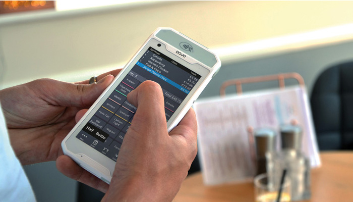 Staff member taking an order at a table using PocketTouch on a Dojo Pocket payment terminal